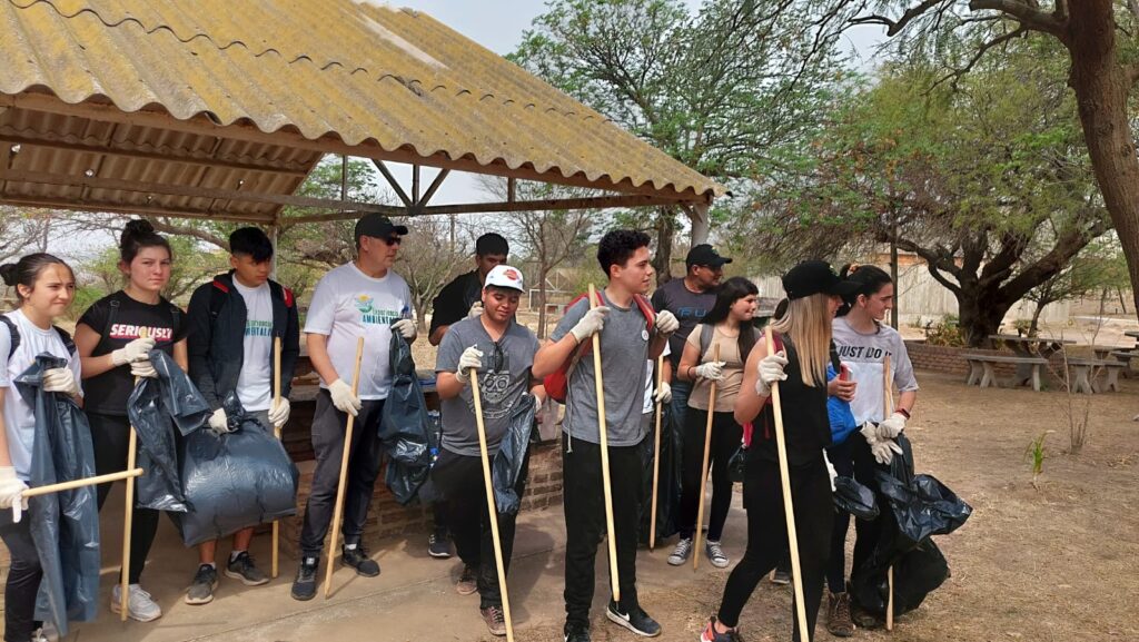 Grupo de jóvenes con pinches y bolsas negras, listos para limpiar el camping Laguna del Plata.